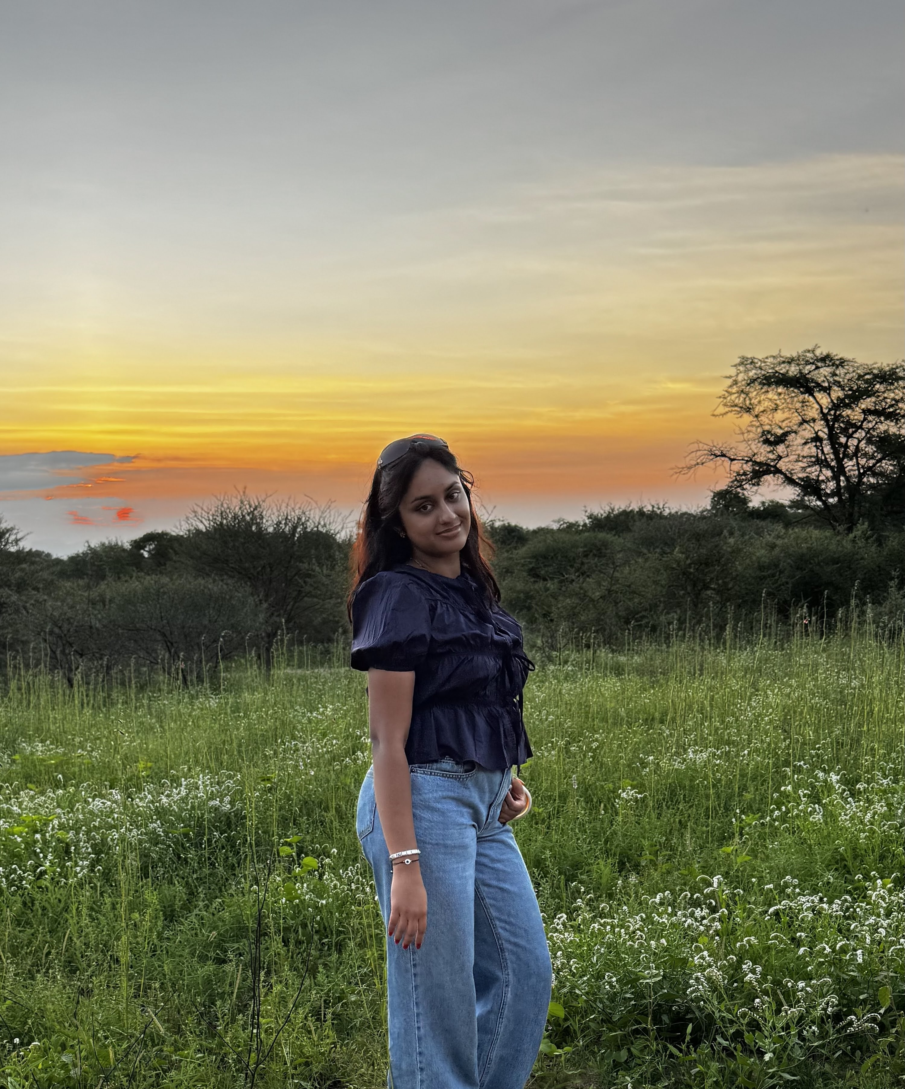 Isha standing in a green field at sunset.